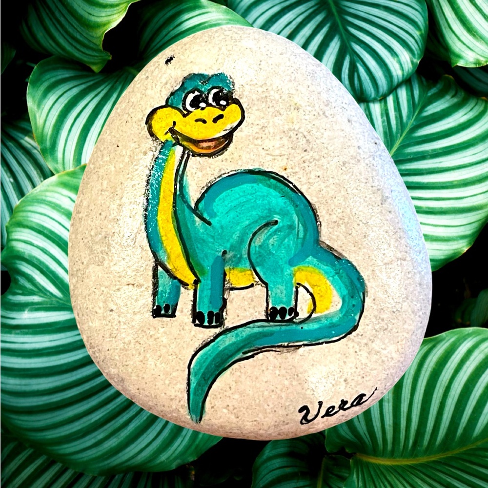 Hand crafted painted dinosaur rock blue black yellow on a white natural stone